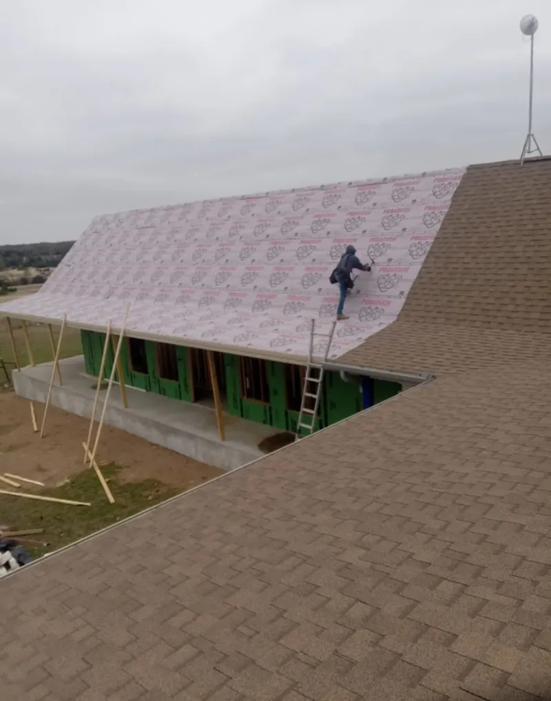 Worker preparing underlayment for a metal roof installation in Cottage Grove
